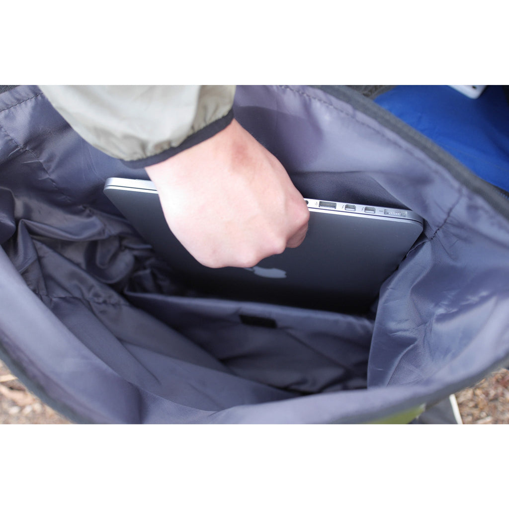 A hand placing a laptop into the padded sleeve inside the dry bag.