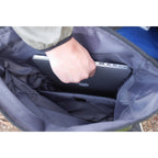 A hand placing a laptop into the padded sleeve inside the dry bag.
